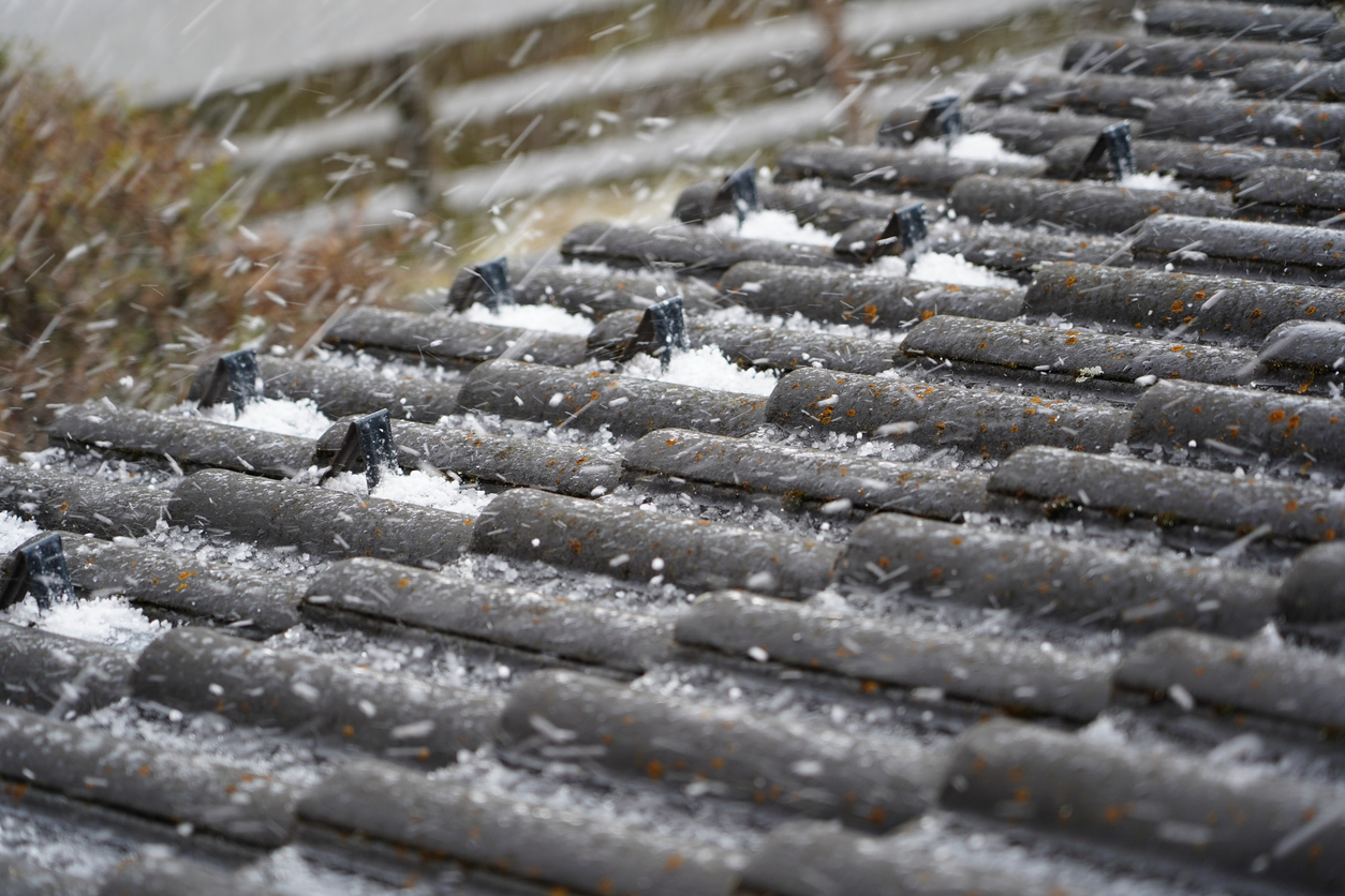 Tiled roof in hail. The roof of a house in Bavaria, Germany. The roof of a private house is black. Hail is falling on the roof.